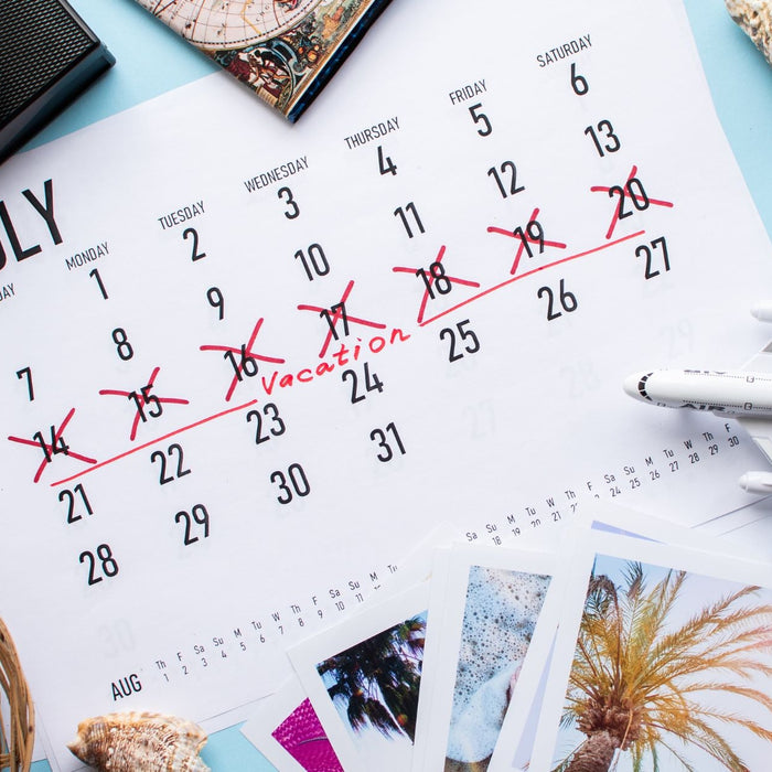 July calendar with days marked off for vacation and vacation trinkets all around.
