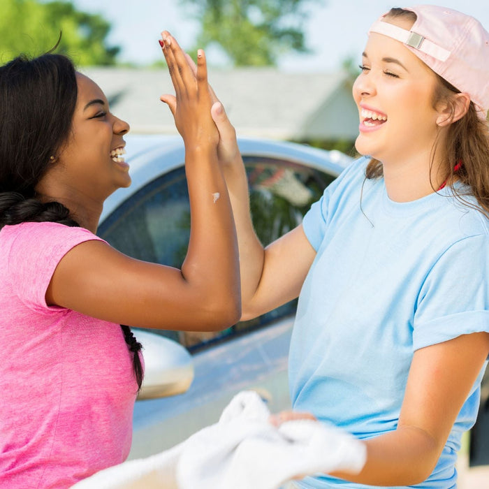 2 students high-fiving at a student-run car wash